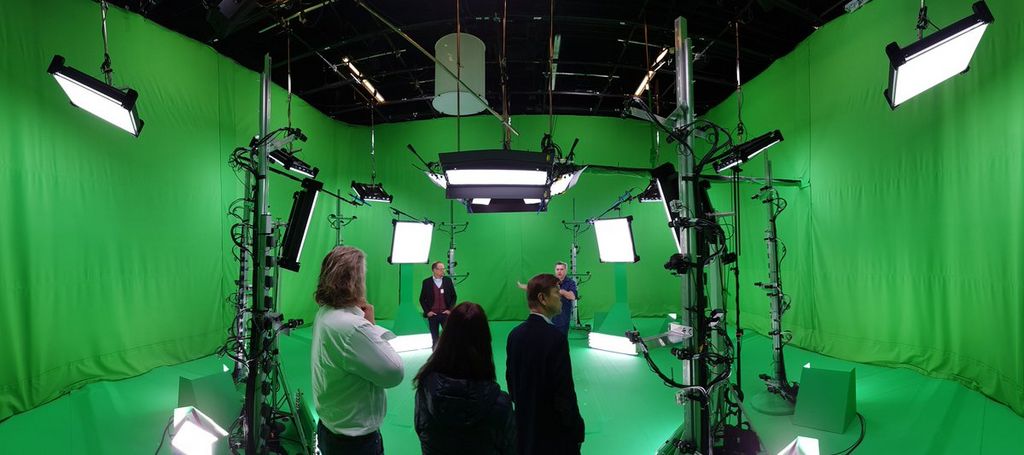 people standing in a big green screen room